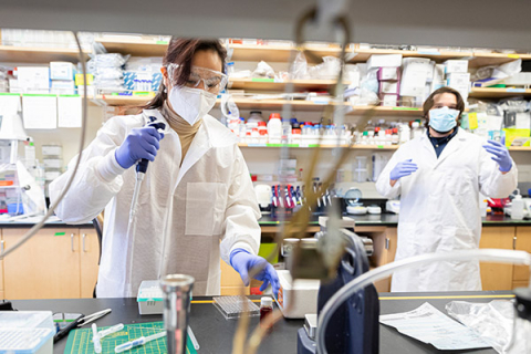 Two people in lab wearing full PPE