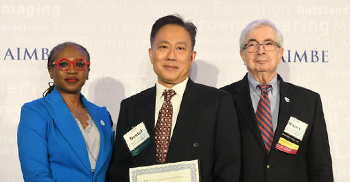 Daniel Chiu holding award alongside two individuals.