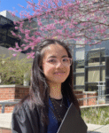 Annie Li standing outside with a building and flowering tree in background.