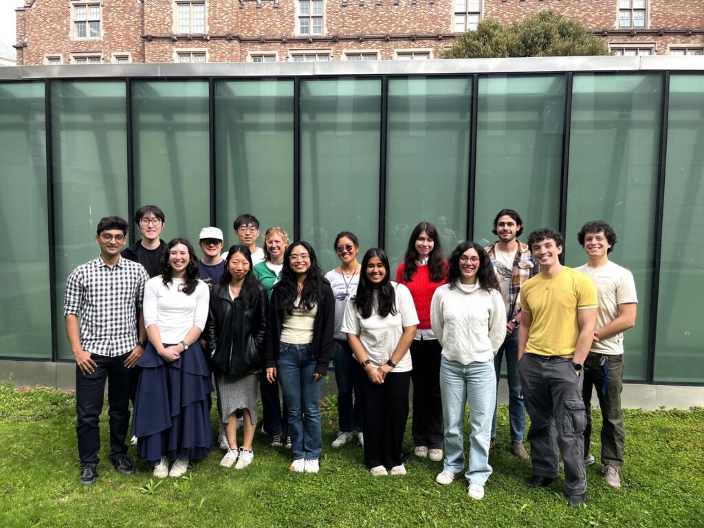 Group of 16 students standing in two rows outside.
